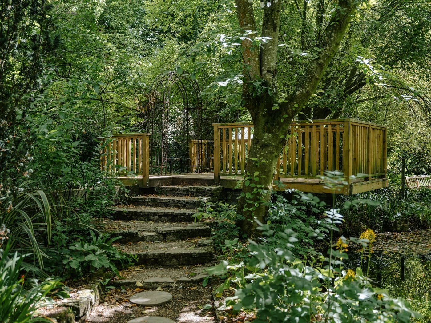 A timber deck with a handrail at the top of stone garden steps